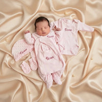 Nouveau-né portant un ensemble naissance rose complet en tissu minky personnalisé avec bonnet et grenouillère.