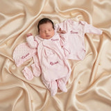 Nouveau-né portant un ensemble naissance rose complet en tissu minky personnalisé avec bonnet et grenouillère.