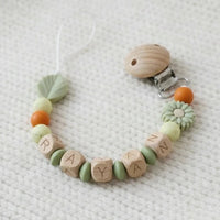Attache tétine MAM personnalisée en silicone et bois, perles marguerite sauge et feuille, tons vert sauge et rouille, longueur 22 cm sans le clip et la tétine.