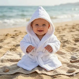 peignoir bebe polaire 2 ans porter par un bébé assis sur le sable avec un fond de place