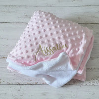 poser sur un fond de bois blanc un plaid bebe polaire de couleur rose personnalisé 