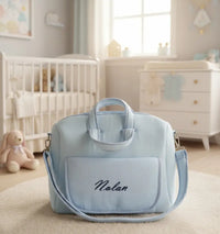 Sac à langer bleu ciel en gaze de coton accroché à une poussette pour illustrer sa praticité